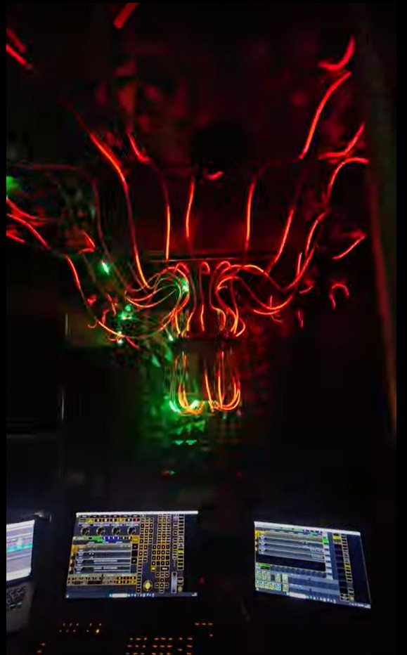 Installation lumineuse rouge et verte, avec postes de programmation au premier plan.