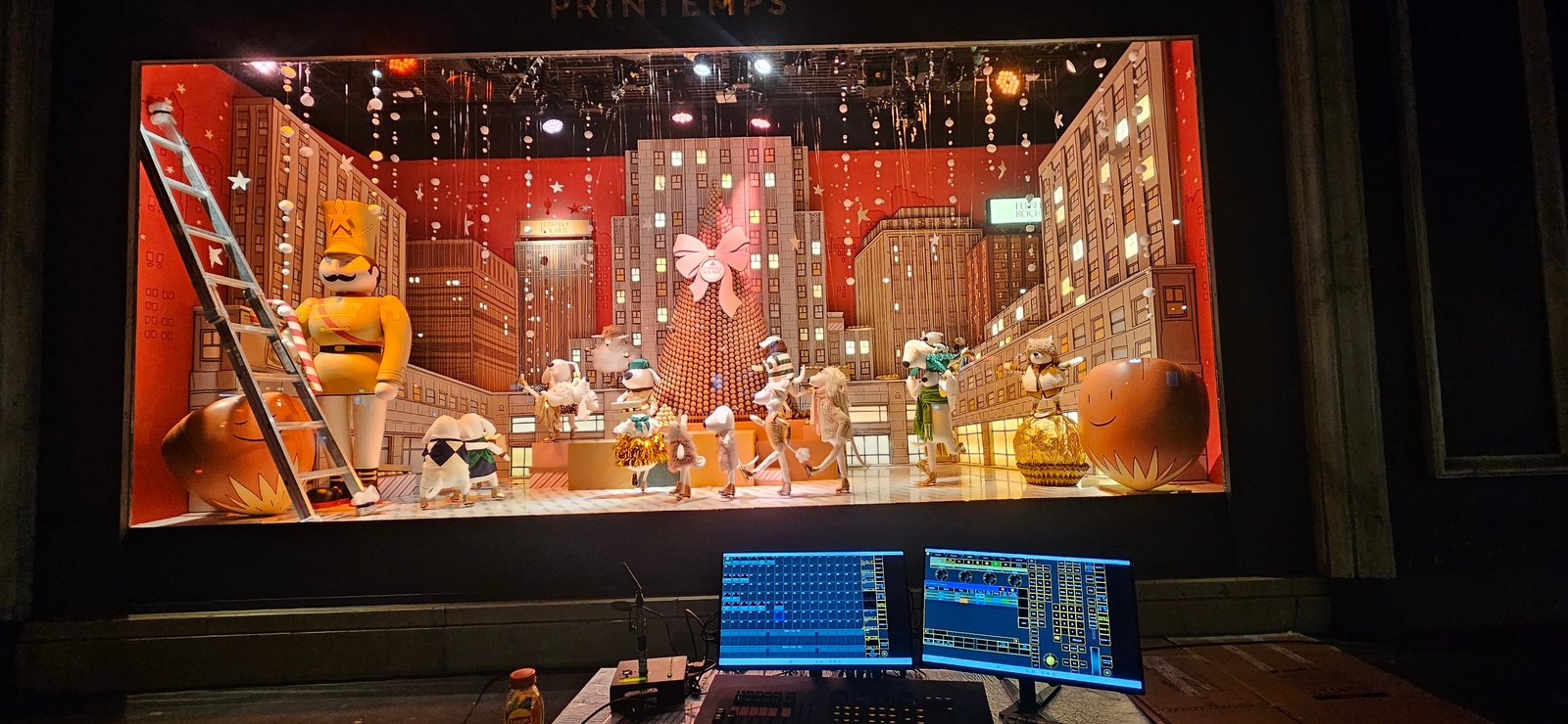 Vitrine de Noël du Printemps éclairée, avec console de programmation au premier plan.